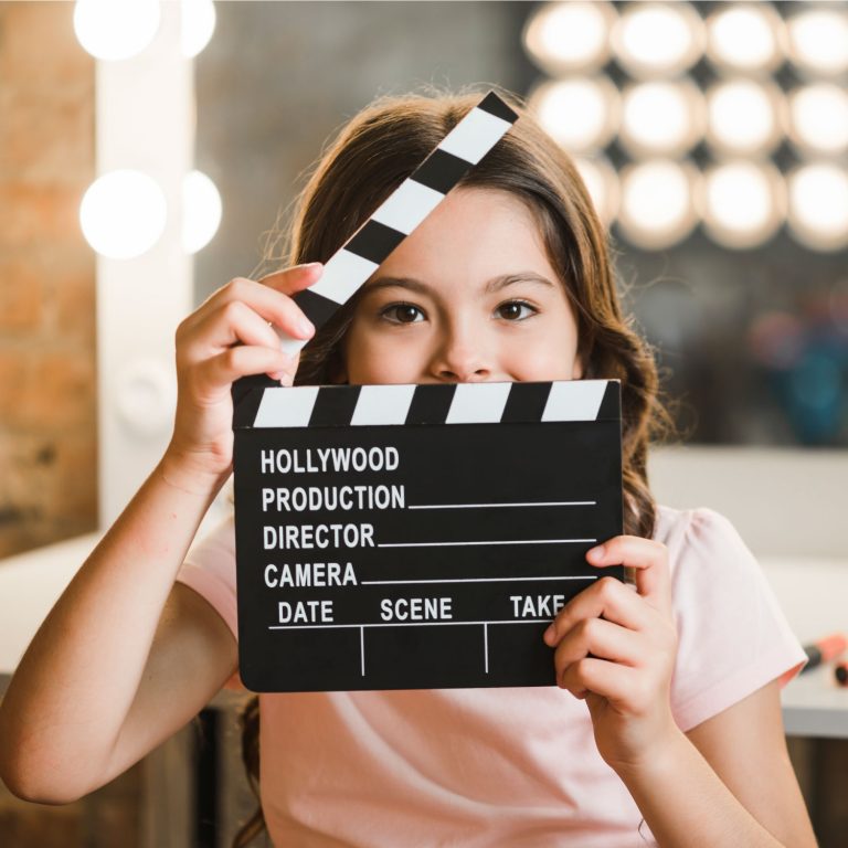 girl-holding-clapperboard-in-front-of-her-mouth